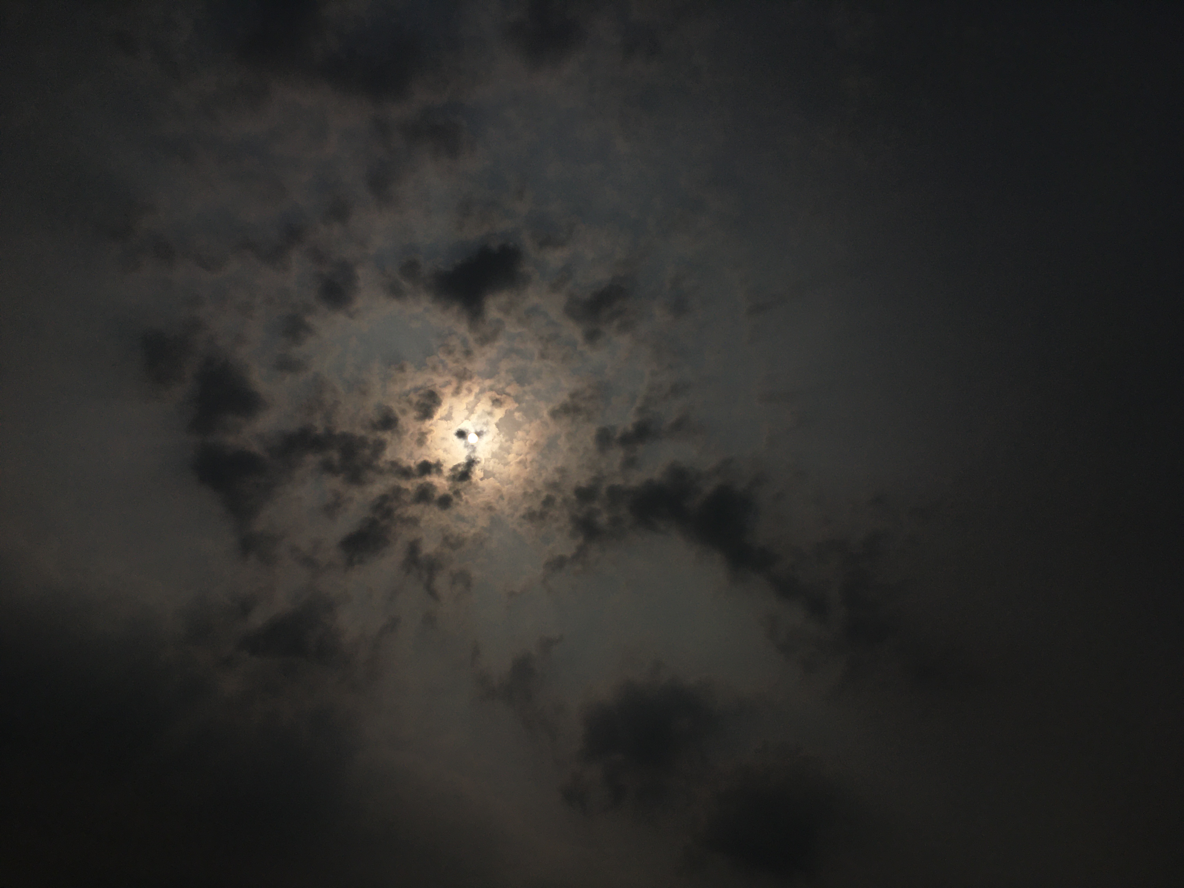 Moon glowing behind dramatic clouds